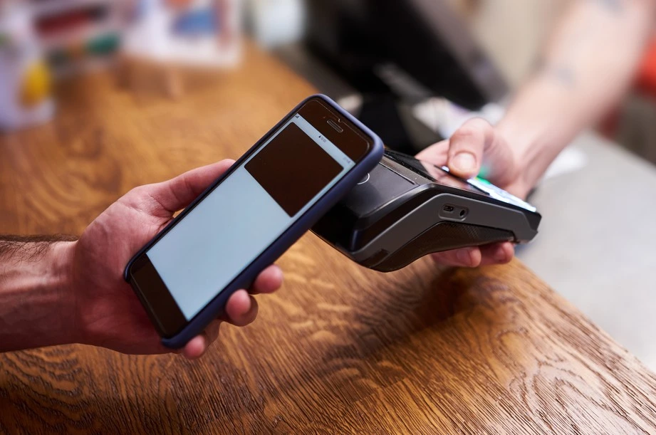 Mobile phone making contactless payment on card reader at store