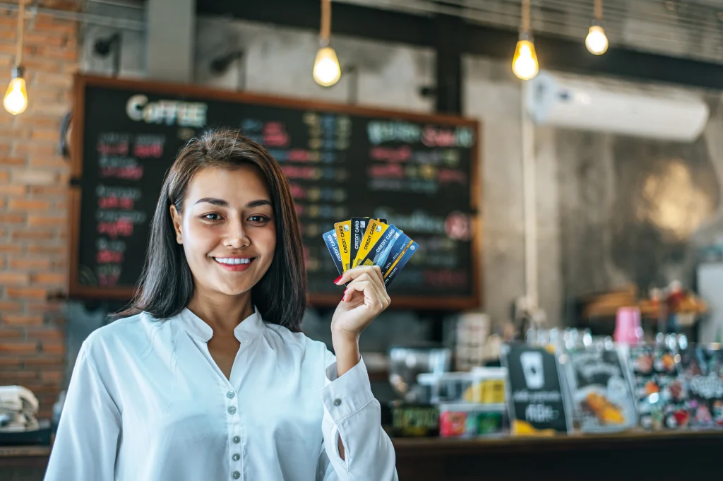 Woman holding multiple credit cards inside a coffee shop