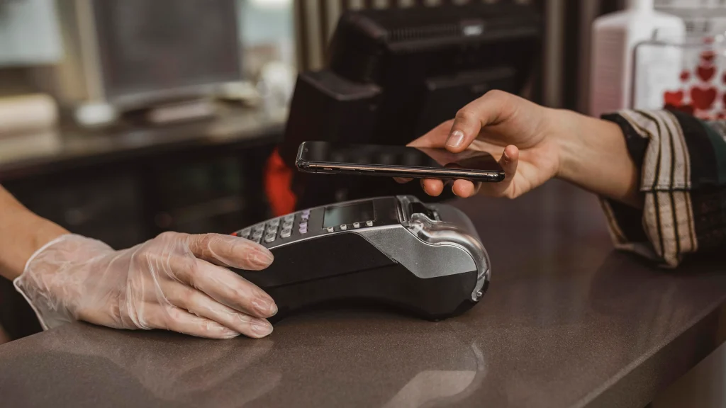 A person pays using a smartphone via contactless technology at a counter.
