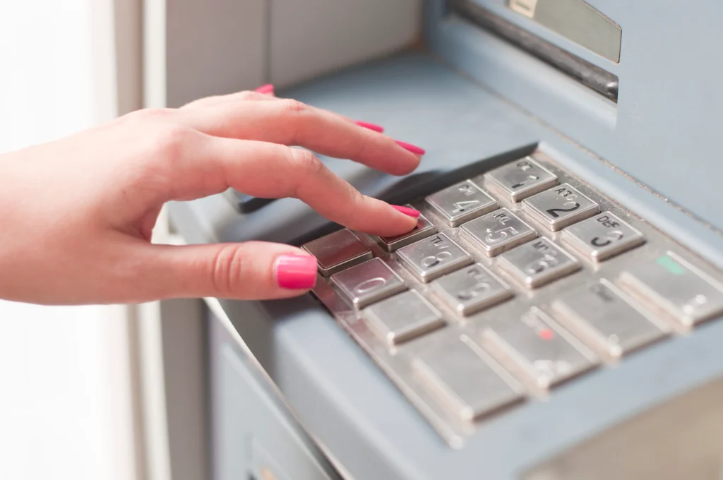 Close-up of hands entering PIN on ATM keypad