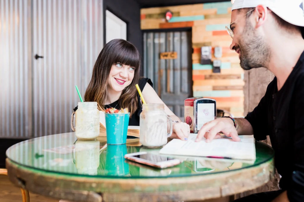 young-woman-pointing-books-cafe-table